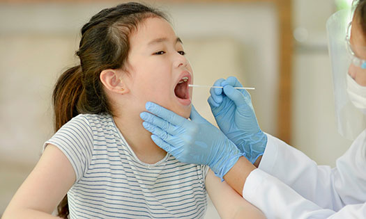 Un médico revisando la garganta de una niña pequeña