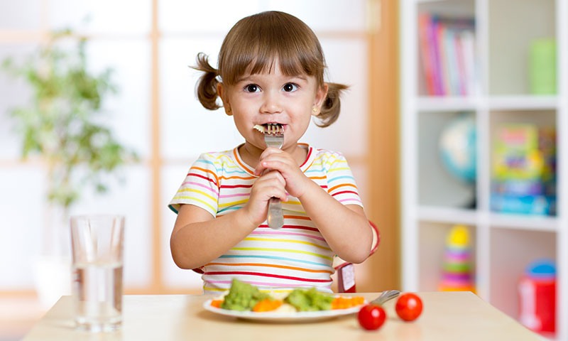 Niña pequeña comiendo un plato saludable de verduras