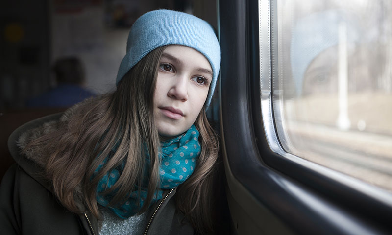 adolescente sentada en el tren mirando por la ventana