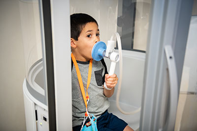little boy performing a pulmonary function test
