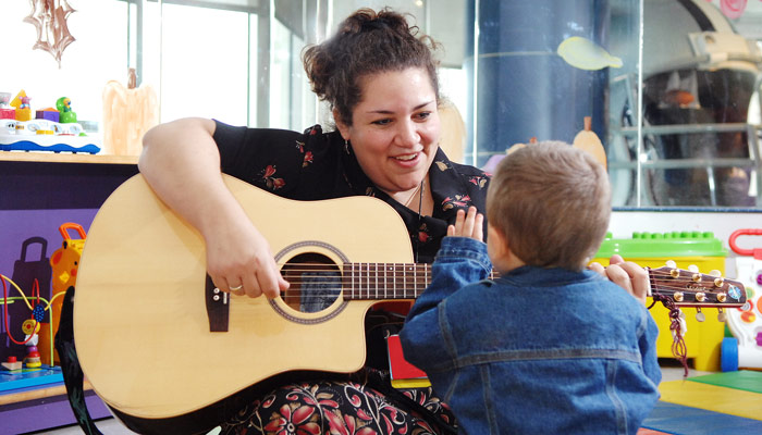 musicoterapeuta tocando la guitarra y cantándole a un niño