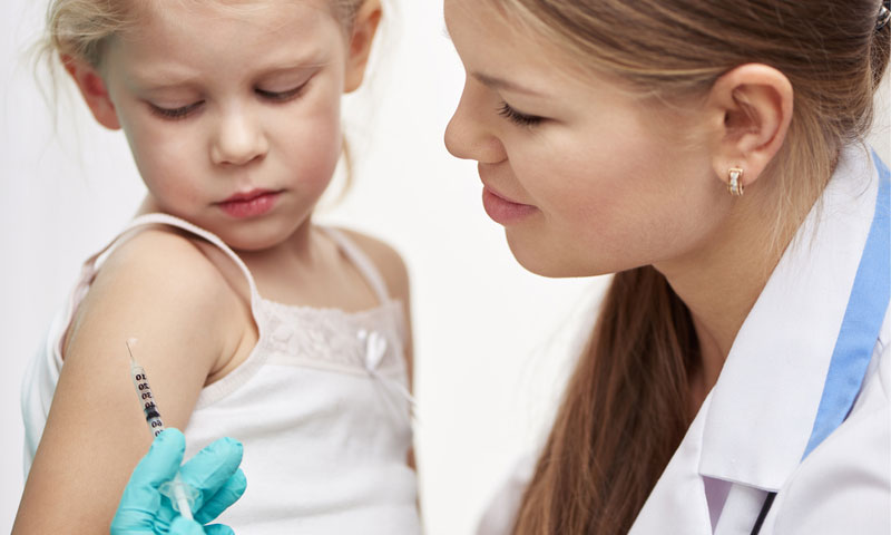 Médica vacunando a una niña pequeña