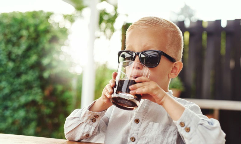 Niño sentado en un patio al aire libre bebiendo un refresco