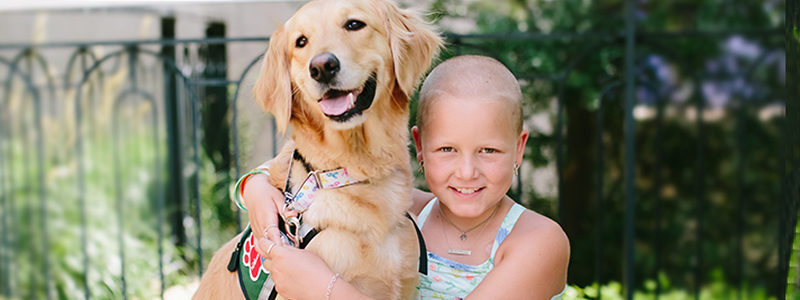 Sadie y Blair, un perro que forma parte de la terapia asistida por mascotas, están abrazados en el jardín Butterfly del centro médico Children's.