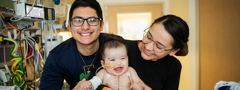 Miles con su mamá y papá riendo solo 10 días después de un trasplante de corazón. El de Miles es el trasplante de corazón número 300 que se ha realizado en el Centro médico Children’s de Dallas.