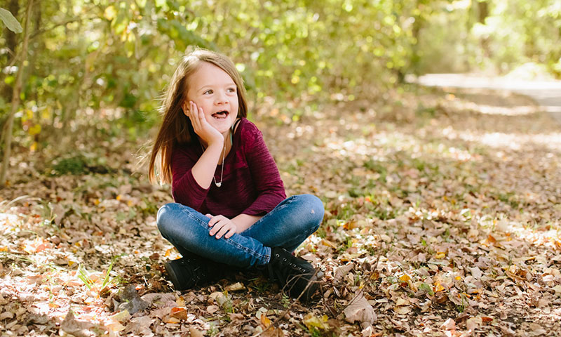 paciente, Bridget sentada sobre algunas hojas en el parque durante el otoño