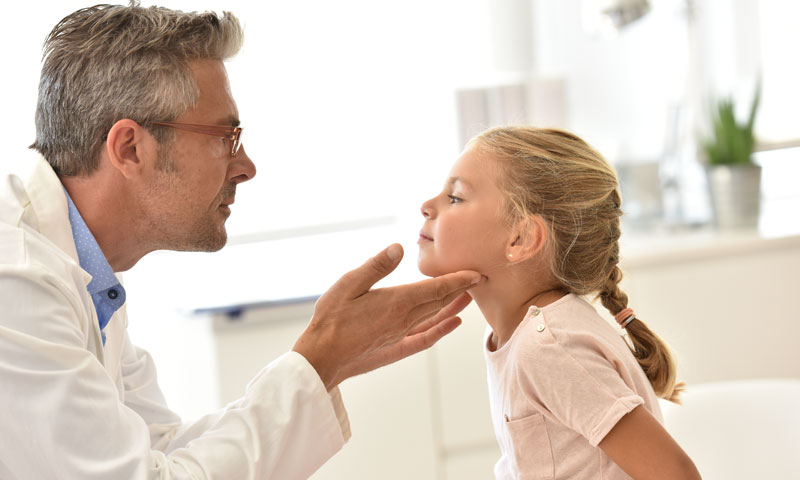 Médico sintiendo la garganta de las niñas pequeñas