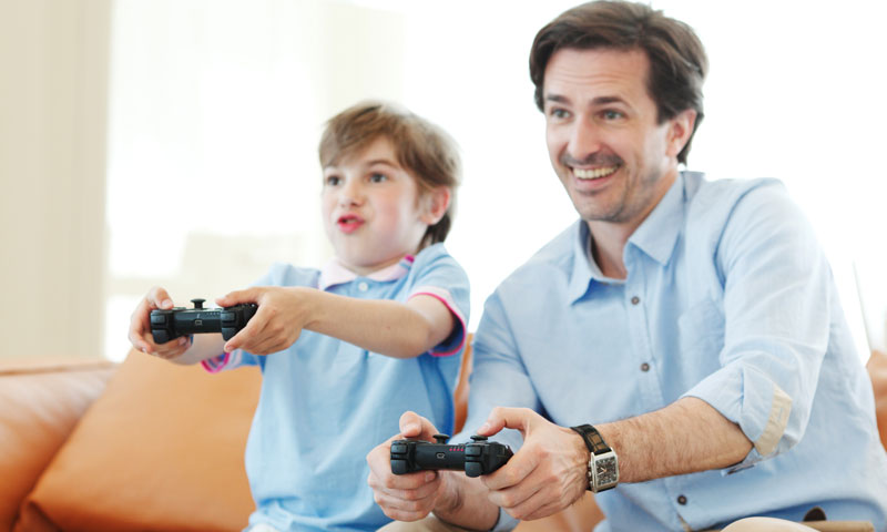 Padre e hijo jugando videojuegos juntos y divirtiéndose
