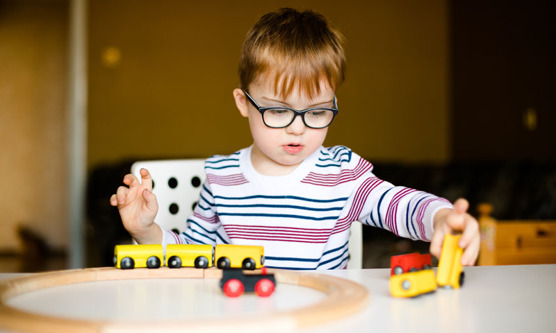 niño jugando con un tren de juguete