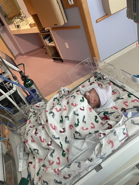 Newborn baby wrapped in a blanket in a hospital.