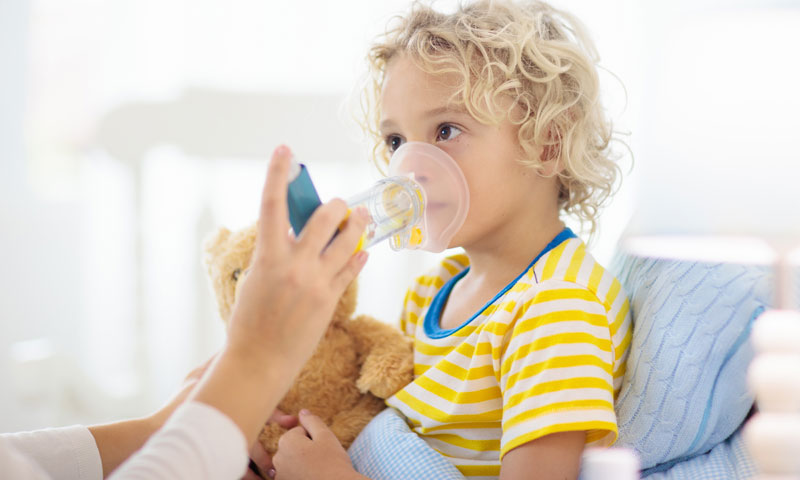 niño usando inhalador para el asma en casa