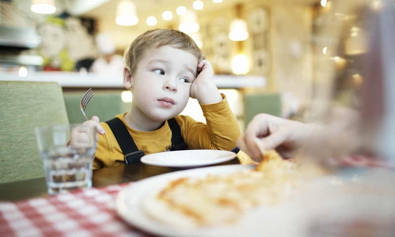 Niño sentado a la mesa con un tenedor en la mano