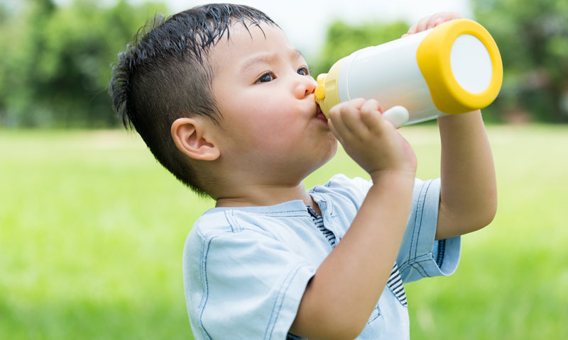 Niño acalorado bebiendo agua al aire libre
