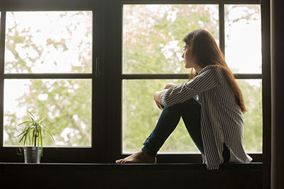 Adolescente deprimida sentada junto a la ventana