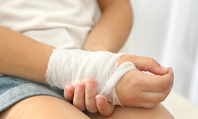 Niña pequeña con una mano lesionada envuelta en una venda