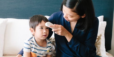 Mom checking little boys temperature.