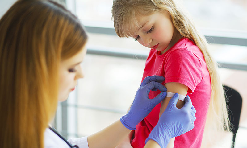 Enfermero colocando una bandita al niño después de recibir la vacuna