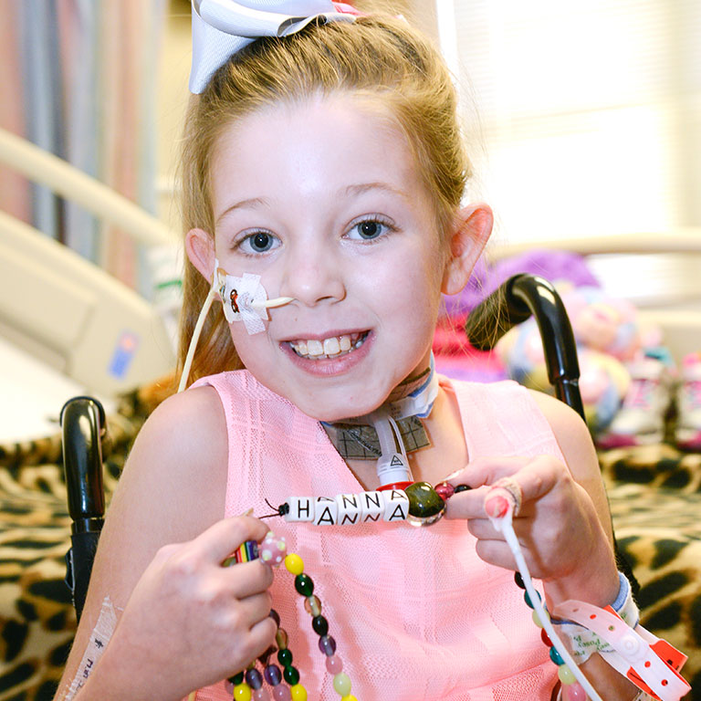 little girl smiling holding a bracelet