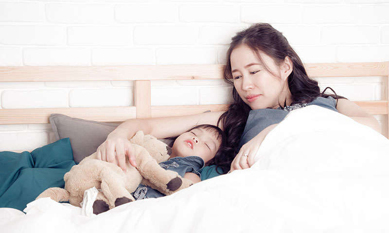 Madre asiática observando a su hijo durmiendo