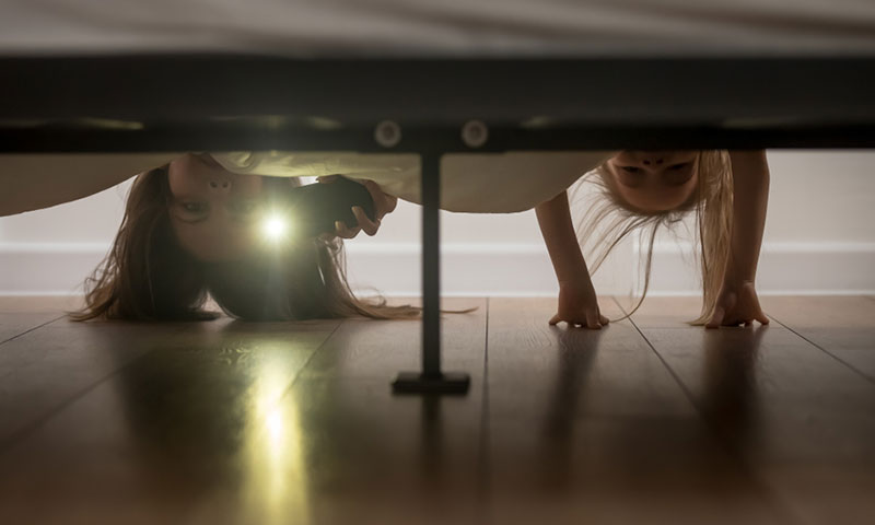 Madre e hija comprobando si hay monstruos debajo de la cama