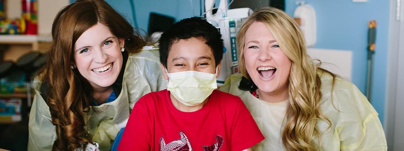 La especialista de vida infantil Katie Foley y Melissa Neely con su paciente Christian en la sala de juegos de Children's Health.