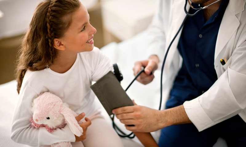 Enfermero controlando la presión arterial de niña pequeña