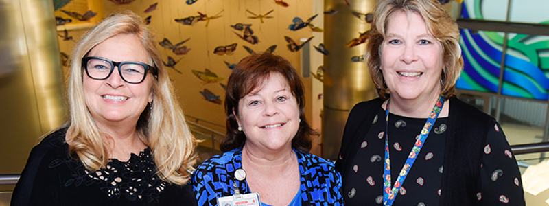 Jenny S. (trabajadora social clínica), Catherine S. (líder del equipo de Trabajo Social) y Laurie W. (administradora de Trabajo Social) posan en el atrio Butterfly